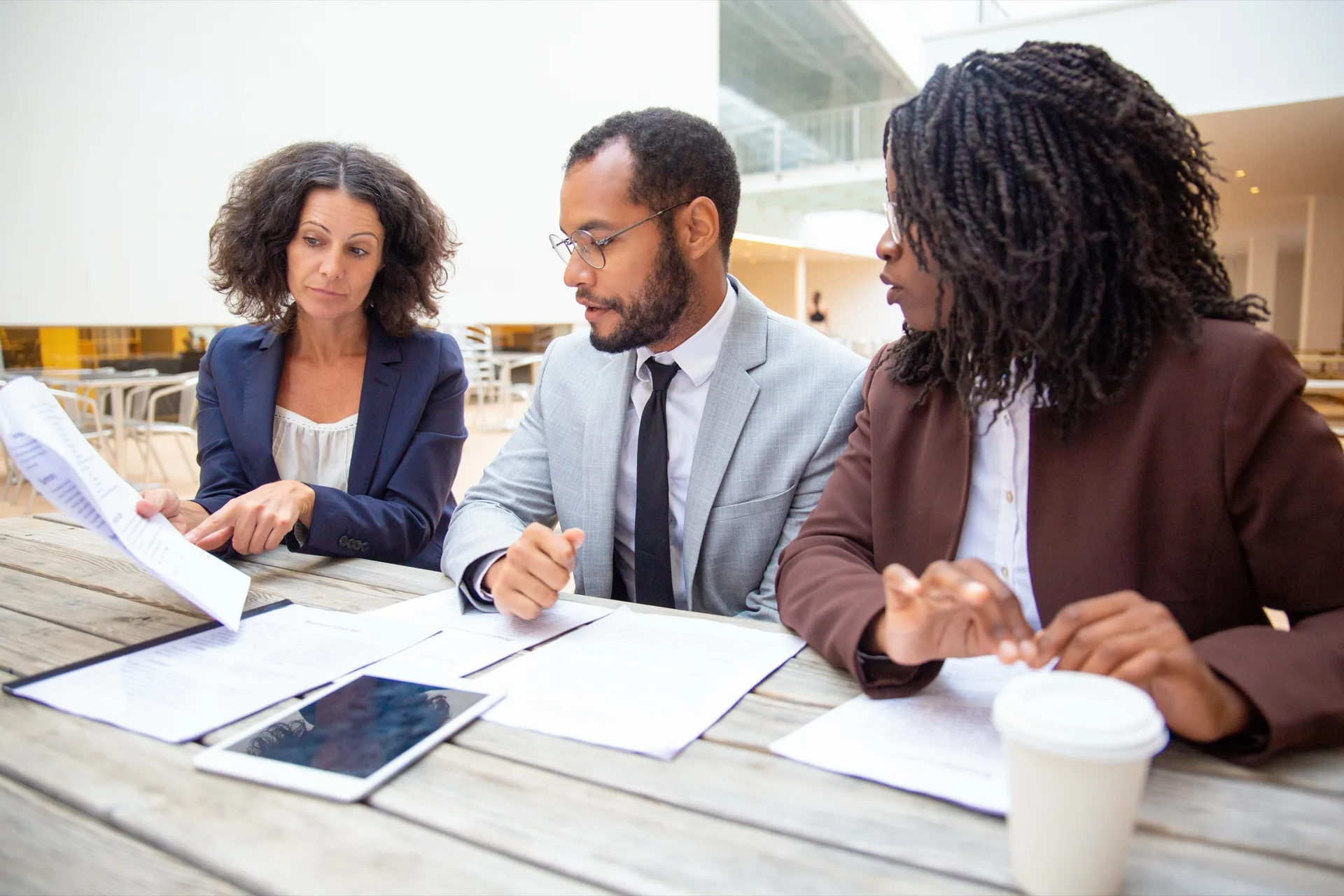 Professionnels africains étudiant ensemble des documents juridiques et financiers dans un atrium moderne.